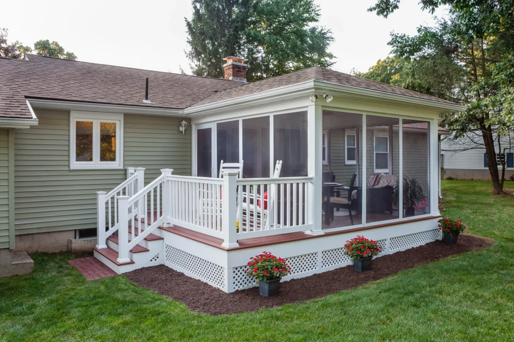 Screened-in porch attached to a home with a small natural timber entry deck and white lattice skirting.